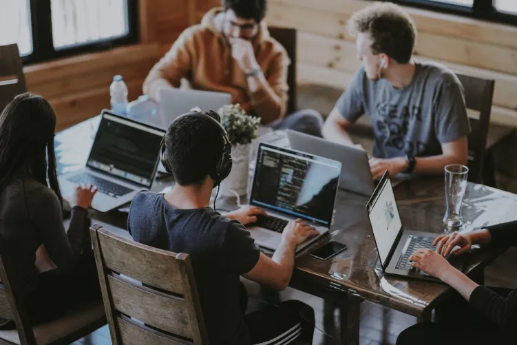 People sat around a desk on laptops