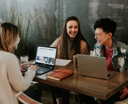 3 people sat around laptops laughing